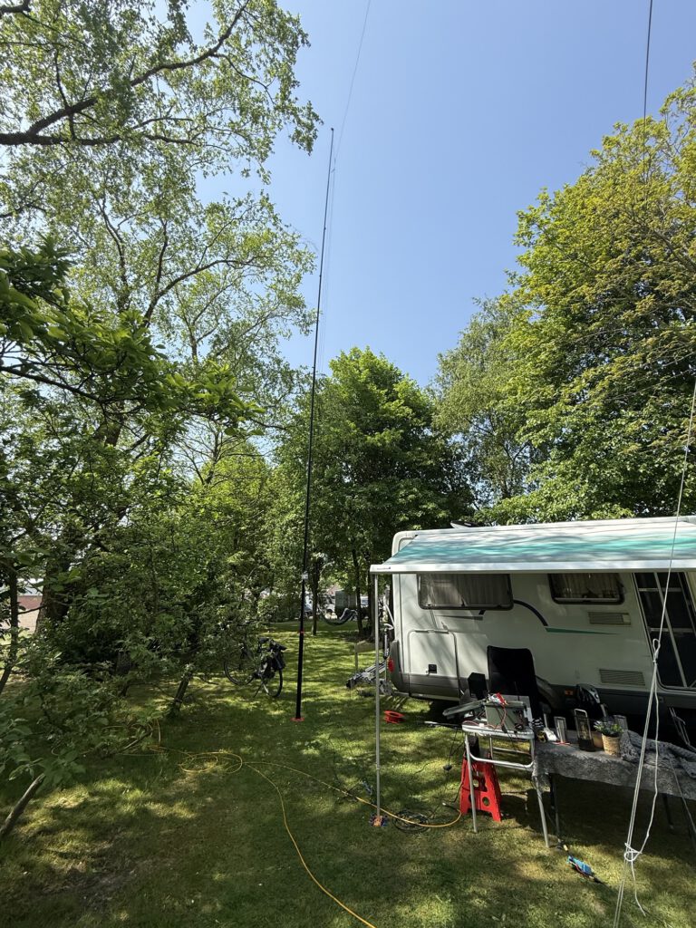 Camper with awning and antenna in the trees